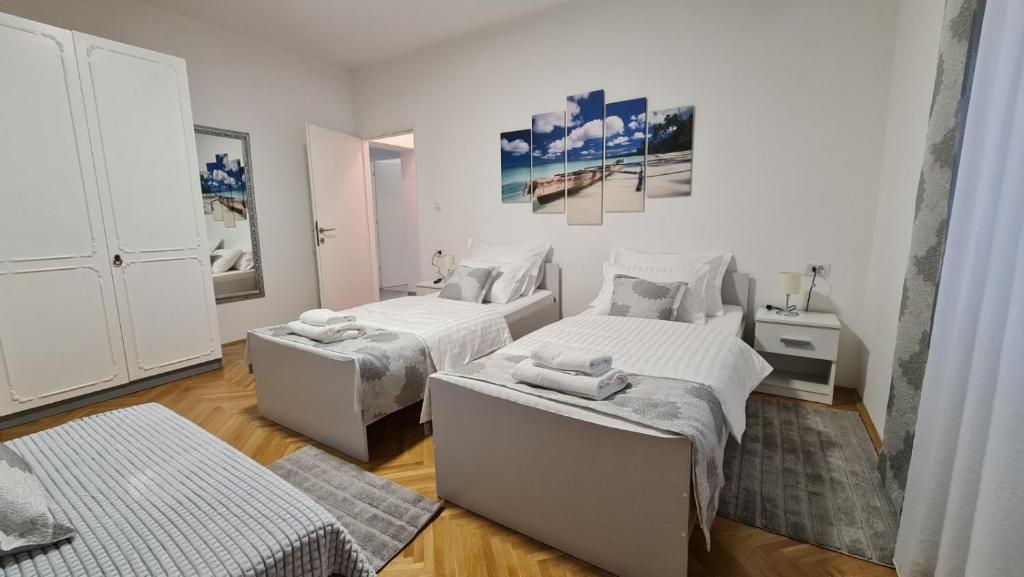 Habitación blanca con 2 camas y mesa en Apartman Magnolija, en Rijeka