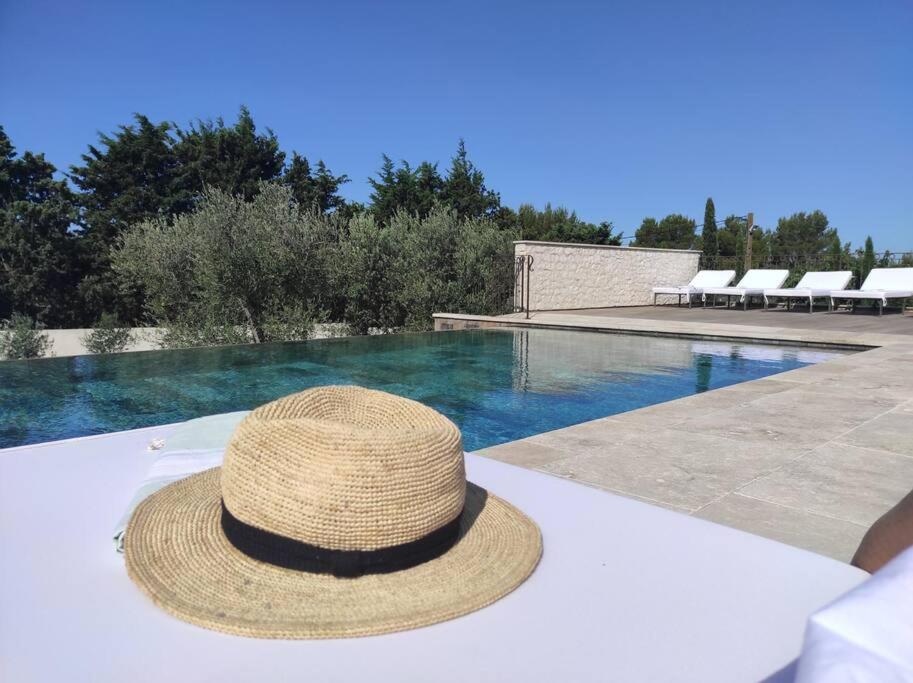 - un chapeau de paille assis sur une table à côté d'une piscine dans l'établissement Magnifique Mas contemporain, à Fontvieille