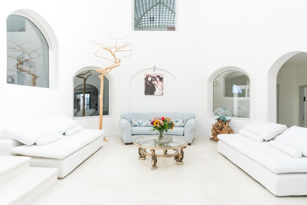 un soggiorno bianco con mobili bianchi e tavolo di Tharroe of Mykonos Boutique Hotel a Mykonos Città
