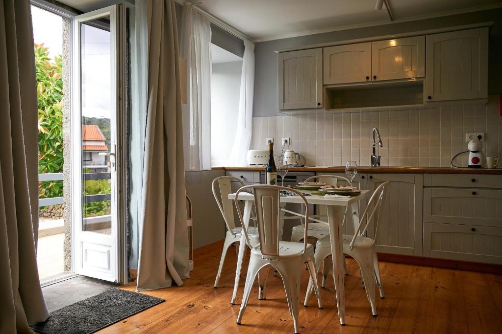 una cocina con mesa y sillas y una puerta abierta en Materramenta, en Biscoitos