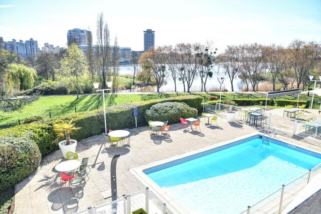 a swimming pool with tables and chairs on a patio at Novotel Paris Créteil Le Lac in Créteil