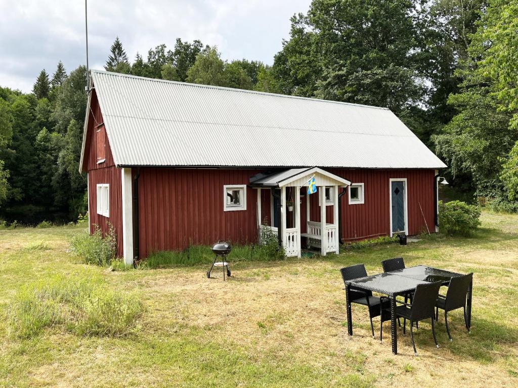 a red barn with a table and chairs in front of it at Red little cottage located in the forest and next to a small lake in Örsjö