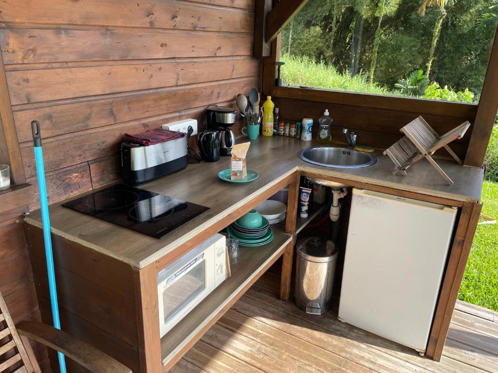 a kitchen in a tiny house with a stove and a sink at Bungalow à flanc de colline in Le Morne Rouge