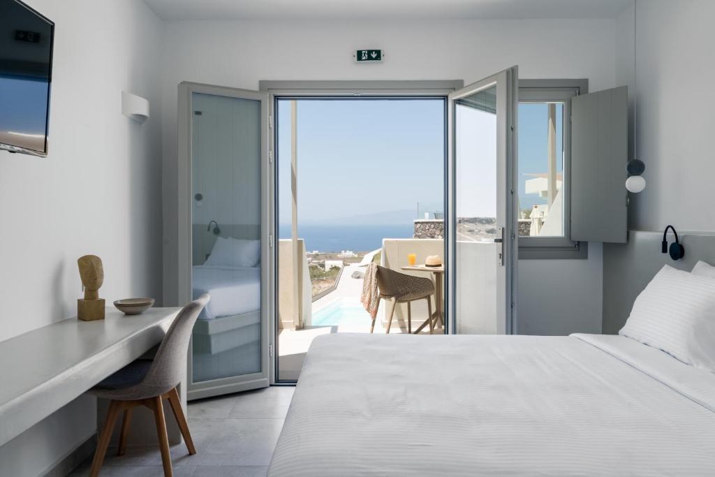 a bedroom with a bed and a view of the ocean at Alegria by Casa Sigalas in Oia