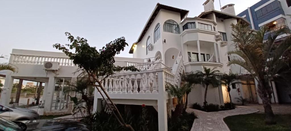 een groot wit huis met een wit balkon bij Czaritza Apart Hotel in Bombinhas