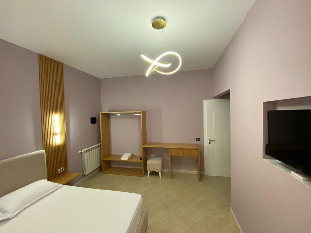 Schlafzimmer mit einem Bett, einem Schreibtisch und einem Deckenventilator in der Unterkunft Hotel Kaloshi in Tirana