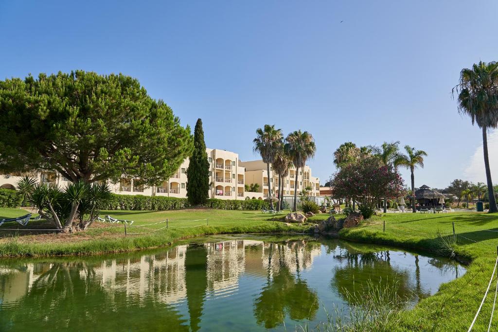 a river in a park with palm trees and buildings at The Navigator - Palm Oasis Alvor - All Inclusive in Alvor