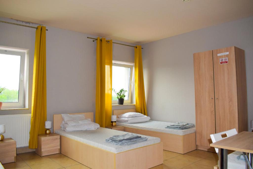 2 łóżka w pokoju z żółtymi zasłonami w obiekcie Noclegi Rzeszów w mieście Rzeszów