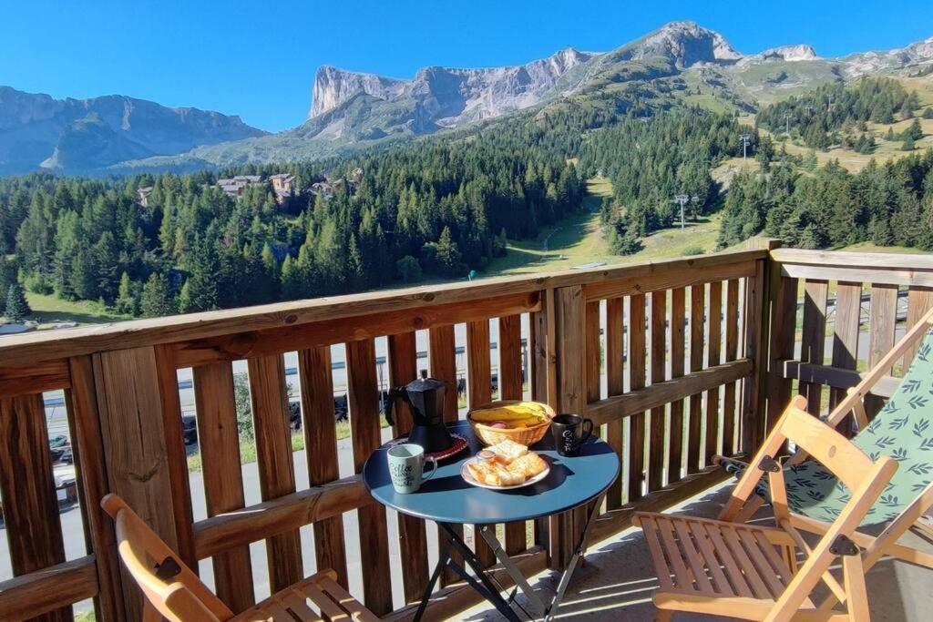 una mesa en un balcón con vistas a las montañas en Appartement 10 personnes au pied des pistes - Superdévoluy, en Superdevoluy
