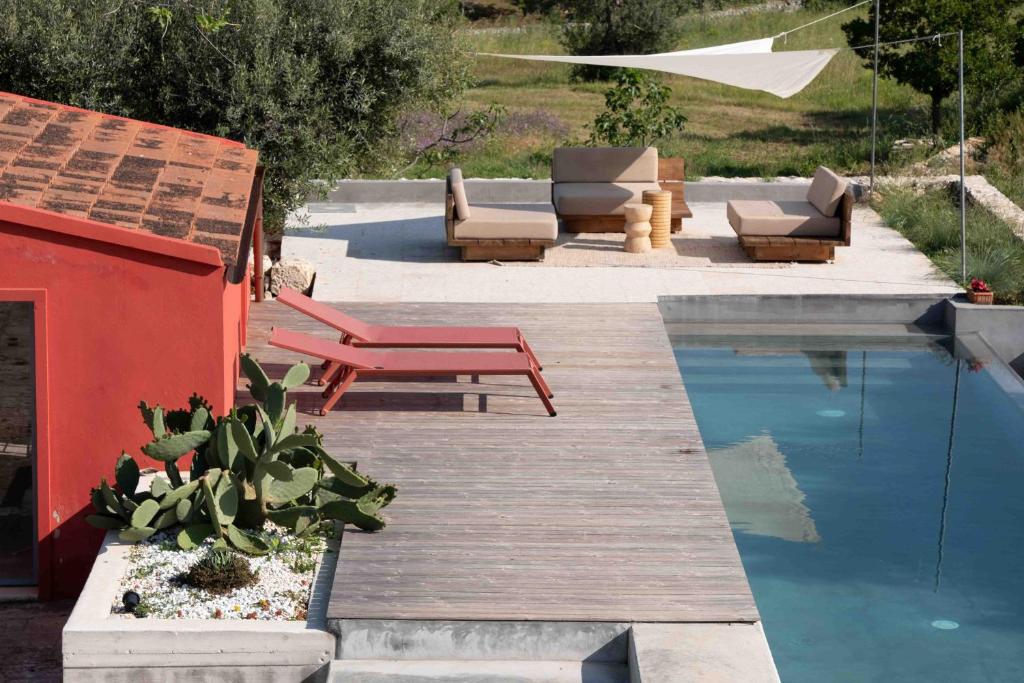 une cour avec une piscine, des chaises et une table dans l'établissement Alloggio nei Trulli della Masseria Collina Casanoja, à Noci