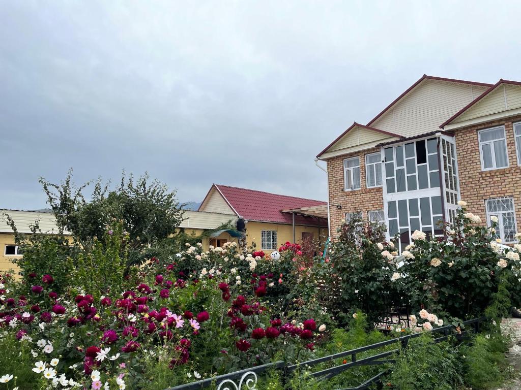 una casa con un jardín de flores delante de ella en Guest House Ugra en Barskoon