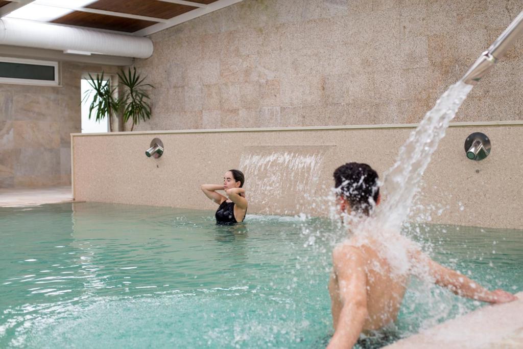 un hombre y una mujer jugando en una fuente en Hotel Do Parque - Congress & SPA, en Termas de Sao Pedro do Sul