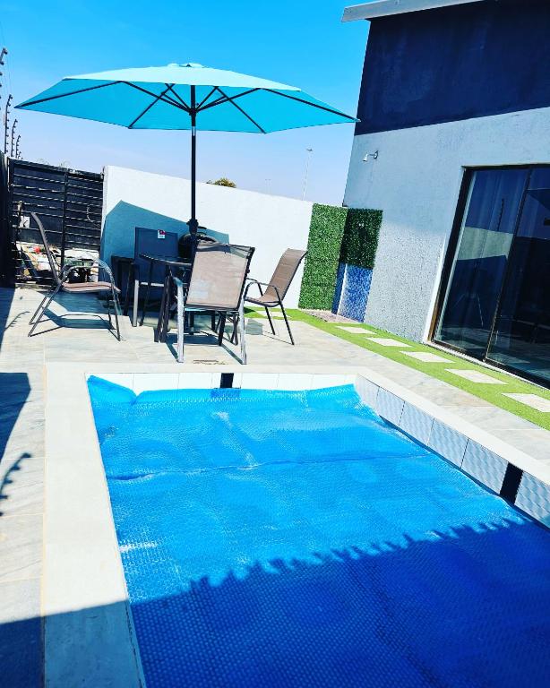 - une piscine bleue avec une table et un parasol dans l'établissement The Pool_deck apartment, à Lebowakgomo