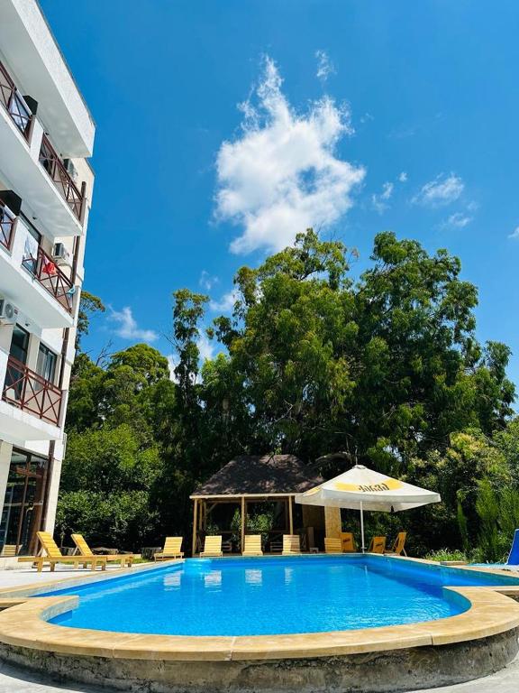 uma grande piscina azul com um guarda-sol e cadeiras em Vita Gardenia Hotel Tskaltubo em Tskaltubo