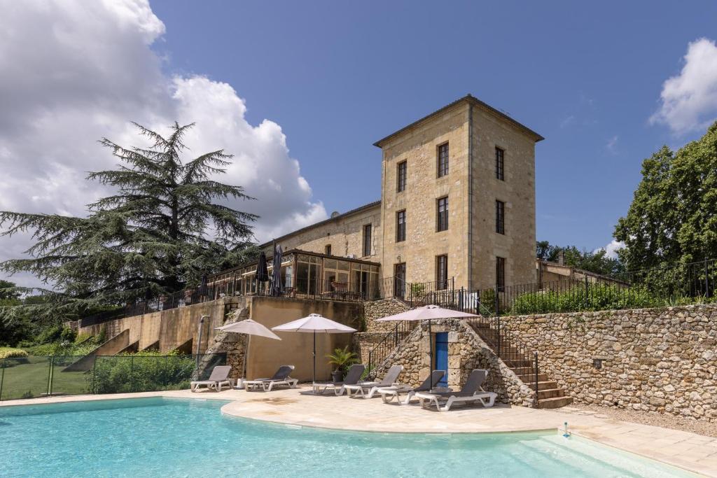 a building with a swimming pool with chairs and umbrellas at Château de Sanse in Sainte-Radegonde