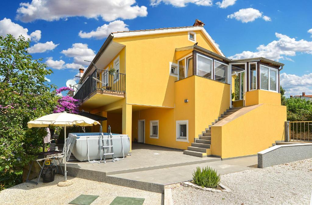 a yellow house with a patio and an umbrella at Apartment Loborika 1411 in Loborika