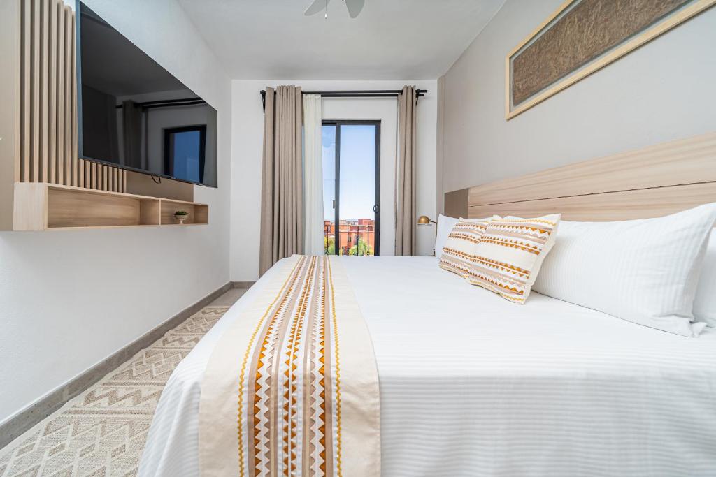 a white bedroom with a large bed with a television at Krystal Grand Residences & Villas San Miguel de Allende in San Miguel de Allende
