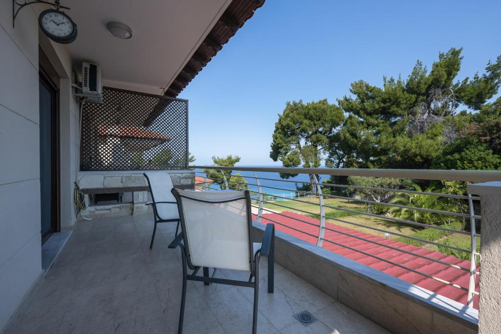 einen Balkon mit Stühlen, einem Tisch und einer Uhr in der Unterkunft #Luxlikehome Seashell Villa in Posidi