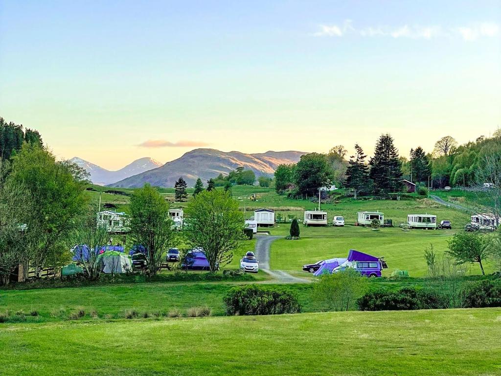 a group of tents in a field with mountains in the background at Cruachan Caravan and Camping Farm in Killin