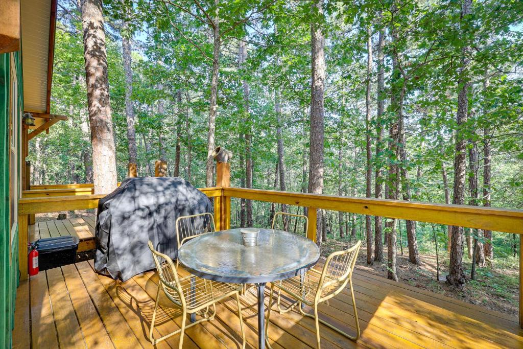 a patio with a table and chairs on a deck with trees at Pet-Friendly Eureka Springs Rental with Private Deck in Eureka Springs