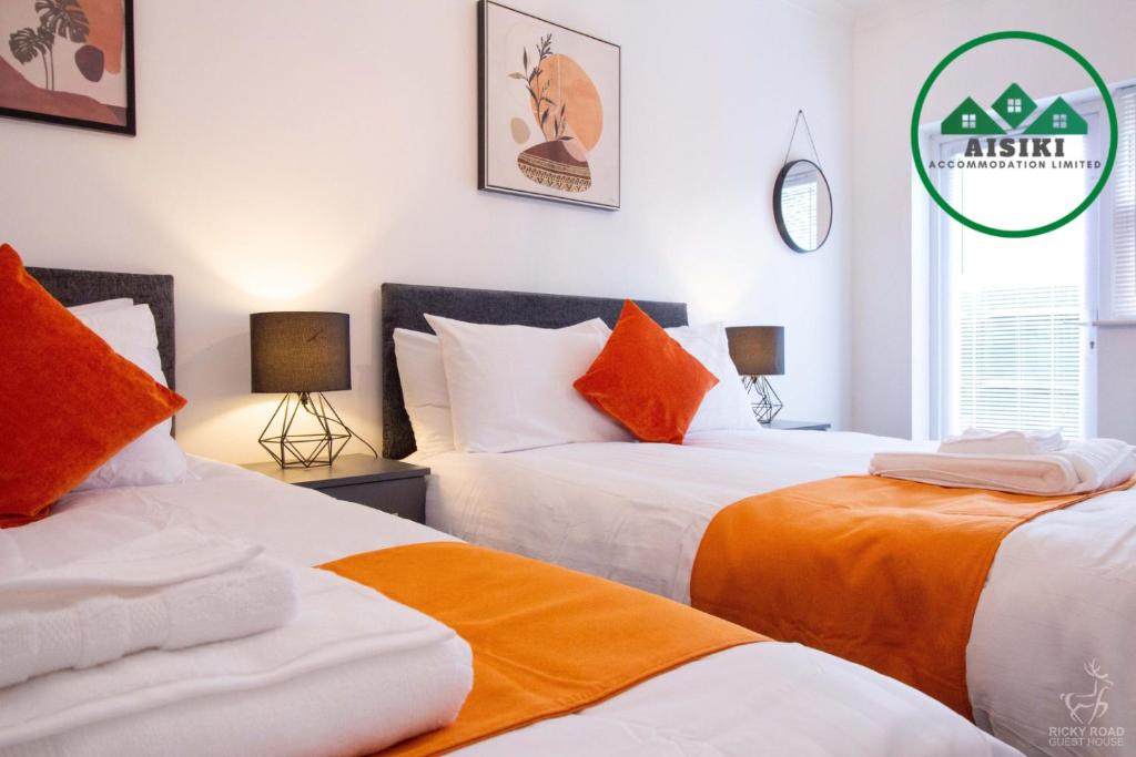 um quarto com 2 camas com lençóis laranja e branco em FW Haute Apartments at Harwoods Road, Multiple 2 Bedroom Pet-Friendly Flats, King or Twin or Double beds with FREE WIFI and PARKING em Watford