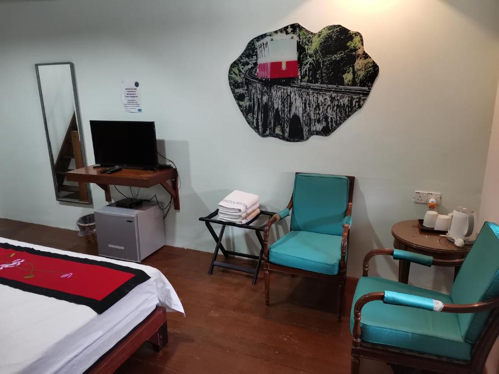 - une chambre avec deux chaises, un lit et un bureau dans l'établissement RANGOON RESIDENCES +, à George Town