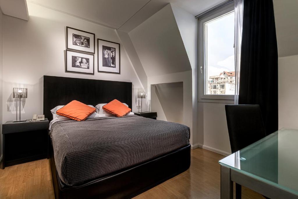 a bedroom with a bed with orange pillows and a window at Broadway Hotel & Suites in Buenos Aires