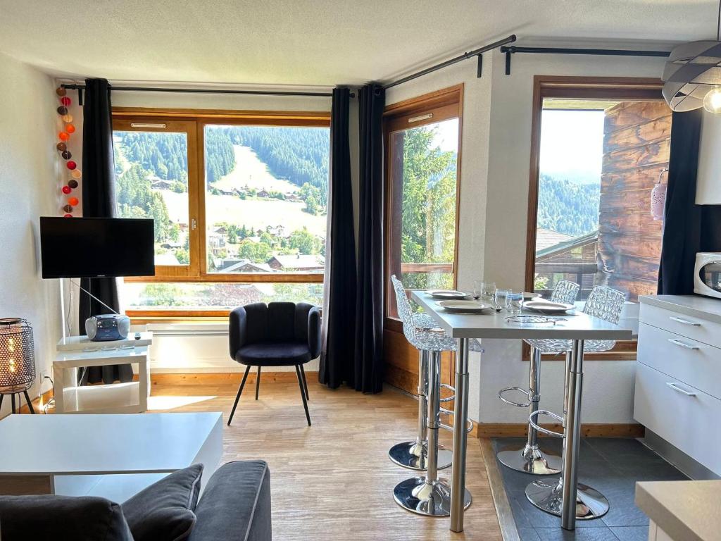 un salon avec une table et une grande fenêtre dans l'établissement Les Gets - Appartement rénové 3 étoiles, face aux pistes, balcon et parking - FR-1-623-294, aux Gets