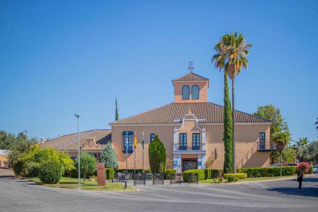a building with a tower and a palm tree at YIT Vereda Real in Valencina de la Concepción