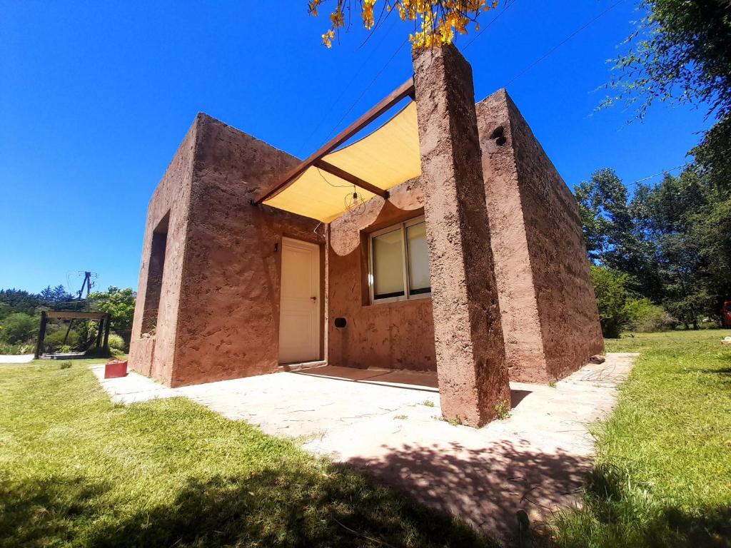 una casa de ladrillo con una puerta blanca en un campo en Los Bambues Cabañas en El Volcán