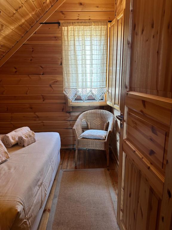 a bedroom with a bed and a chair and a window at Chalé Inn Star in Penhas da Saúde