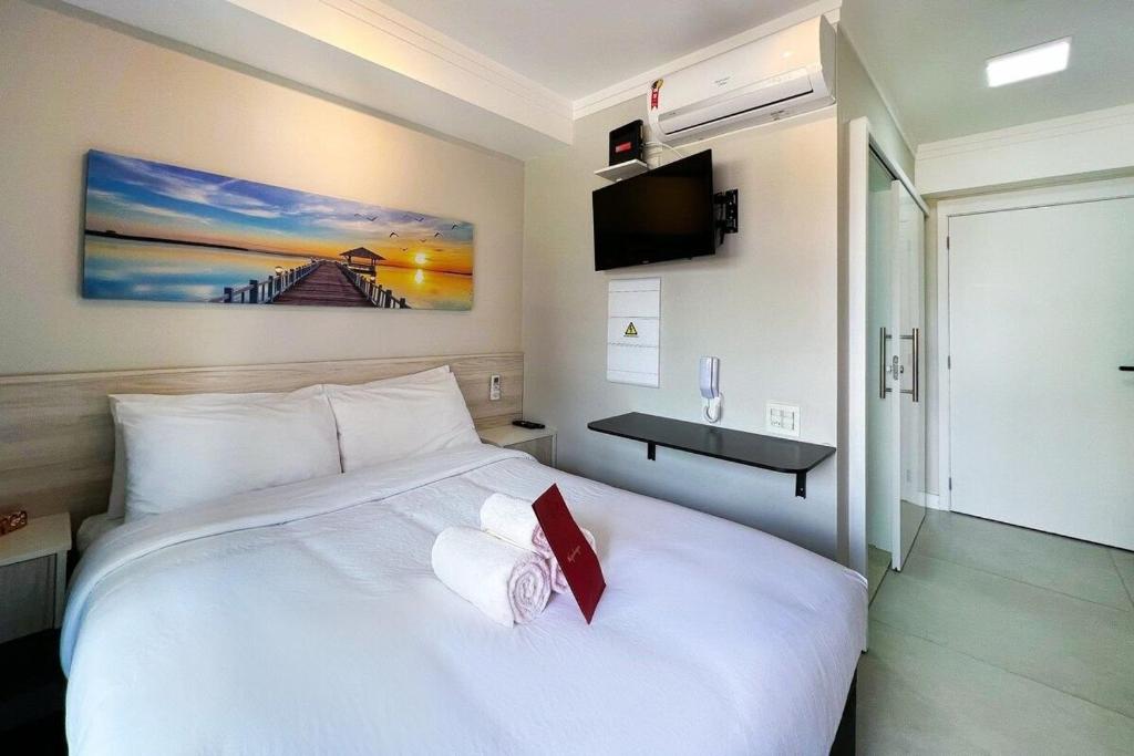Habitación de hotel con cama blanca grande y TV en Zainalofts7 Moema - 1km Ibira e 200m metrô 202 ID, en São Paulo
