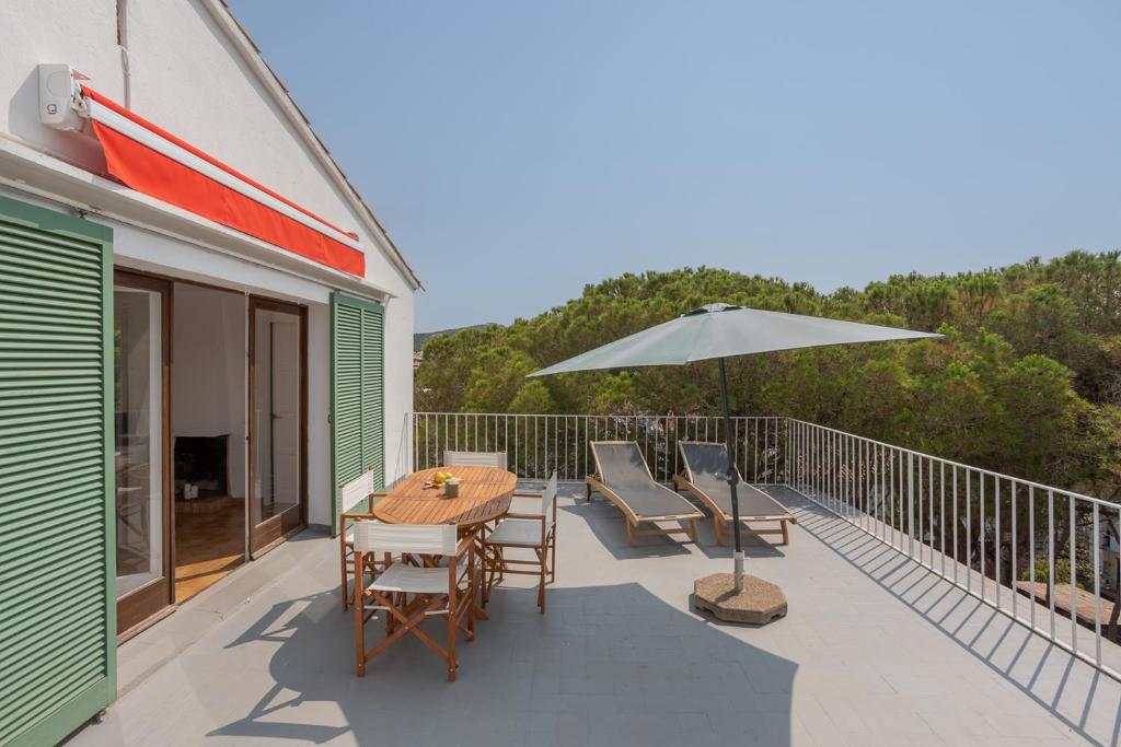 a patio with a table and chairs and an umbrella at Apartamentos CASA MAREA Calella Palafrugell con Parking in Calella de Palafrugell