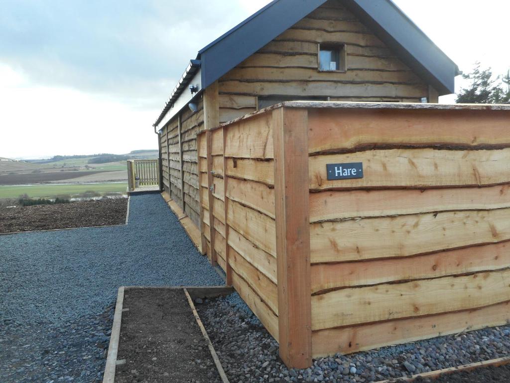 a wooden building with a sign that says hate at Hare Lodge with Hot Tub in Cupar