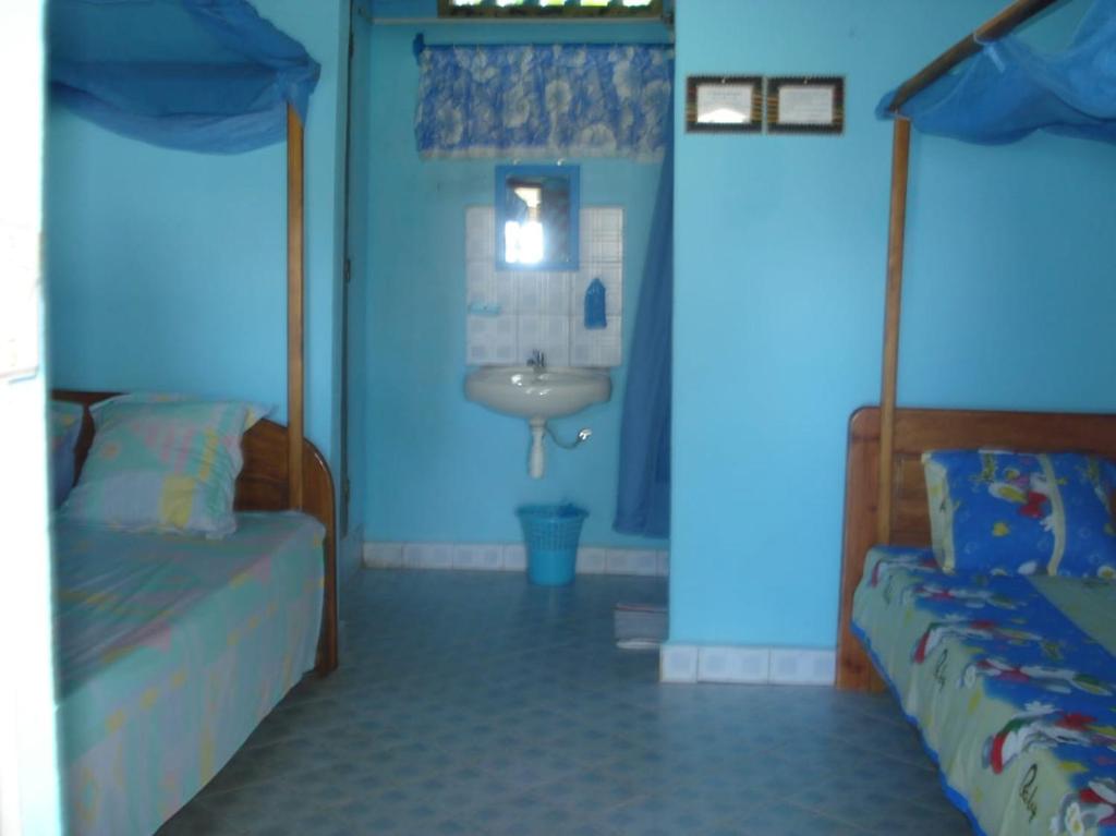 uma casa de banho com 2 camas e um lavatório num quarto em Bungalow le Charme, au bord de la mer 