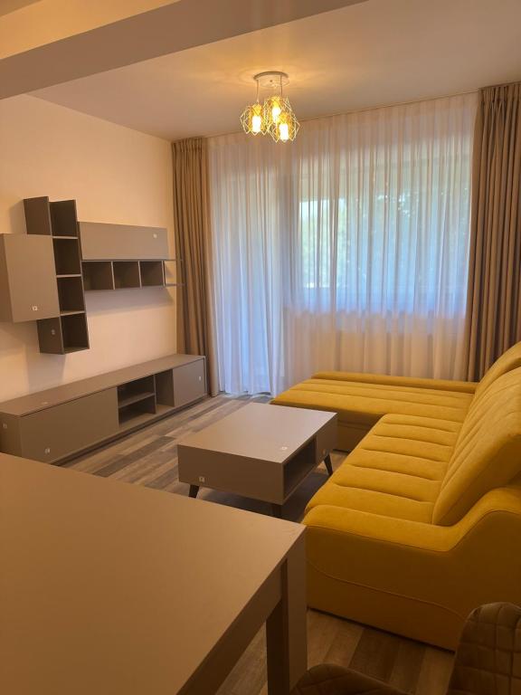 uma sala de estar com um sofá amarelo e uma mesa em IN APART HOTEL em Bucareste
