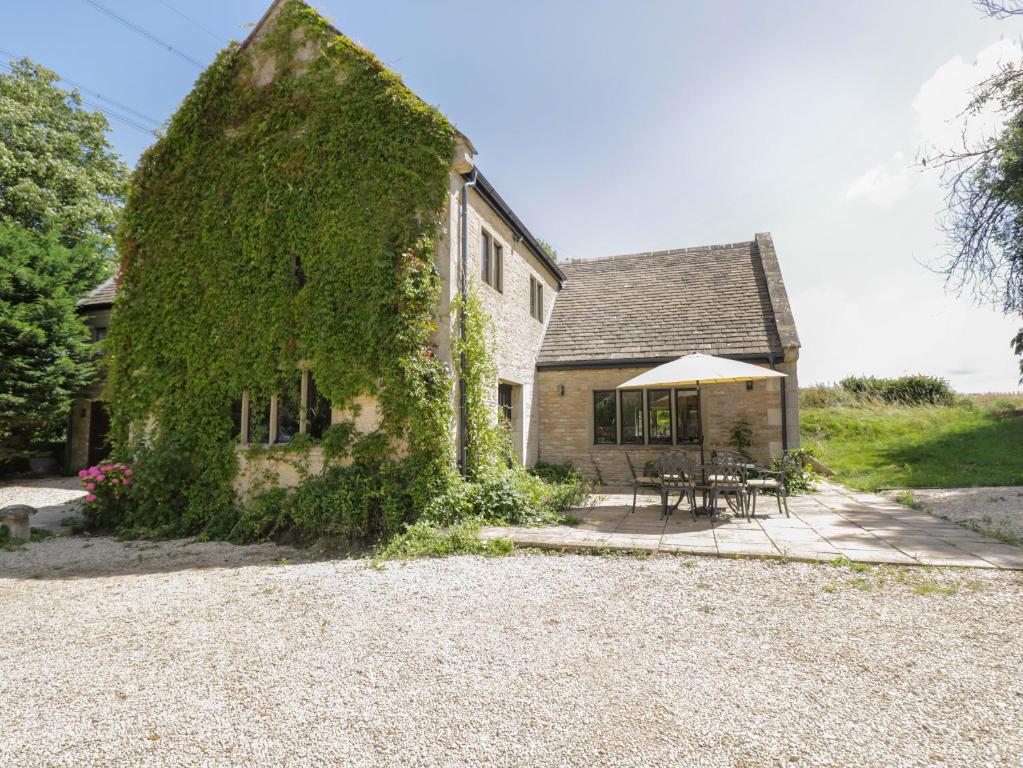 an ivy covered house with a table and chairs at Paddock Barn in Chippenham