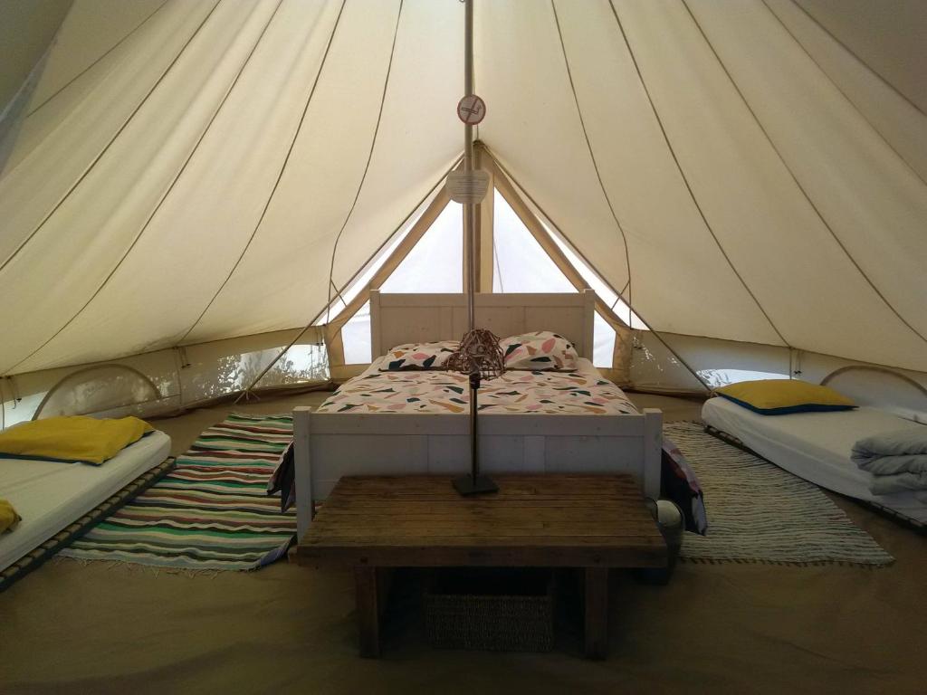 a tent with two beds and a table in it at Yourte et tente dans un écolieu avec piscine hors-sol in Péault