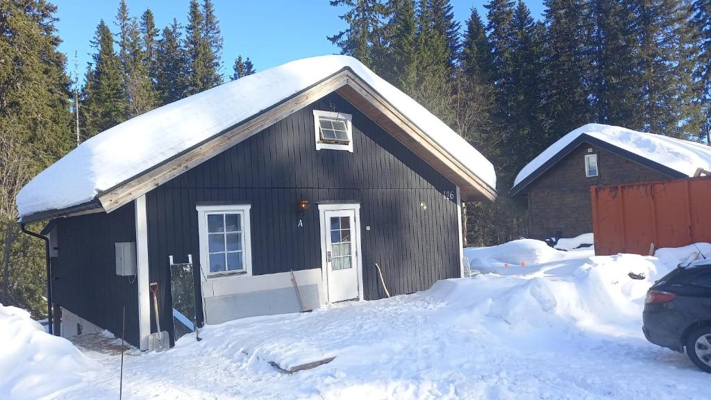 una casa negra con nieve en el techo en Apartment in Lindvallen, en Sälen