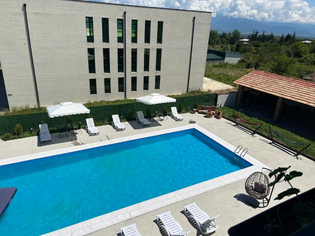 una piscina con sillas y sombrillas frente a un edificio en Green Hotel ANG, en Telavi