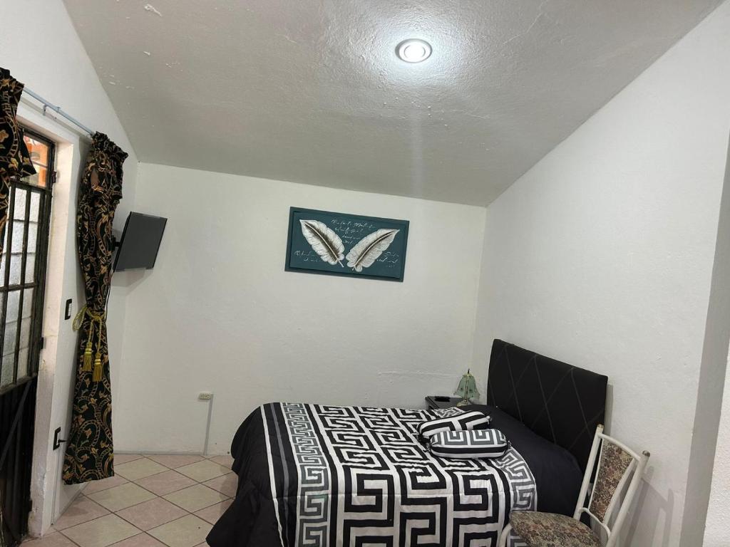 ein Schlafzimmer mit einem Bett und einem Bild an der Wand in der Unterkunft Carpe Diem in Zacatlán