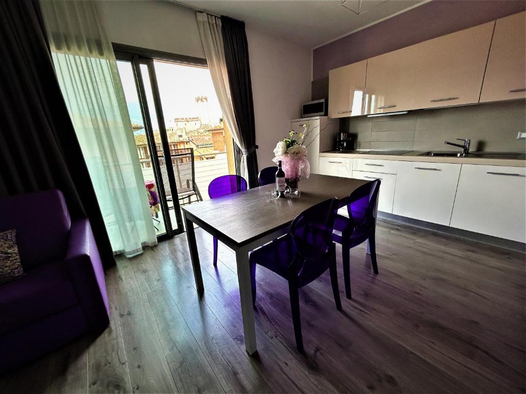 a dining room table with purple chairs in a kitchen at Gardesana Active Apartments in Malcesine
