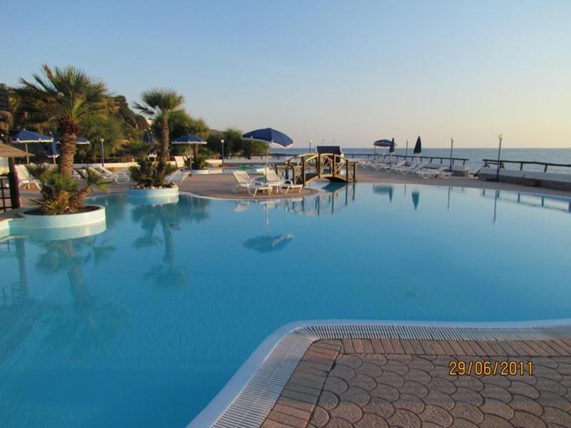 a large blue swimming pool next to the ocean at Villaggio Hotel Agrumeto in Capo Vaticano