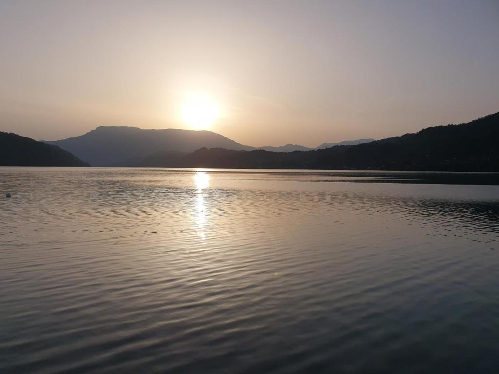 a sunset on a lake with mountains in the background at Apartman Relax Čelebići in Konjic