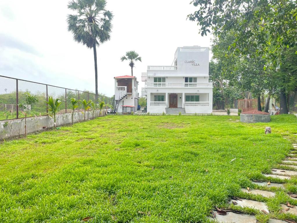 un gran patio de césped frente a una casa blanca en Classic Villa en Pālghar