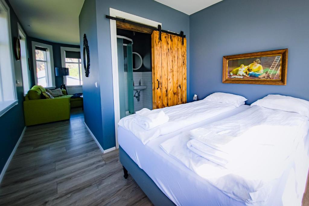 1 dormitorio con 1 cama grande y pared azul en Guesthouse Holl, en Vestmannaeyjar