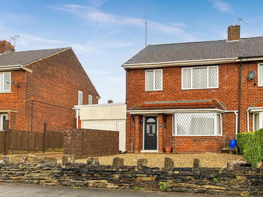 a brick house with a stone fence in front of it at Harris House in Staveley