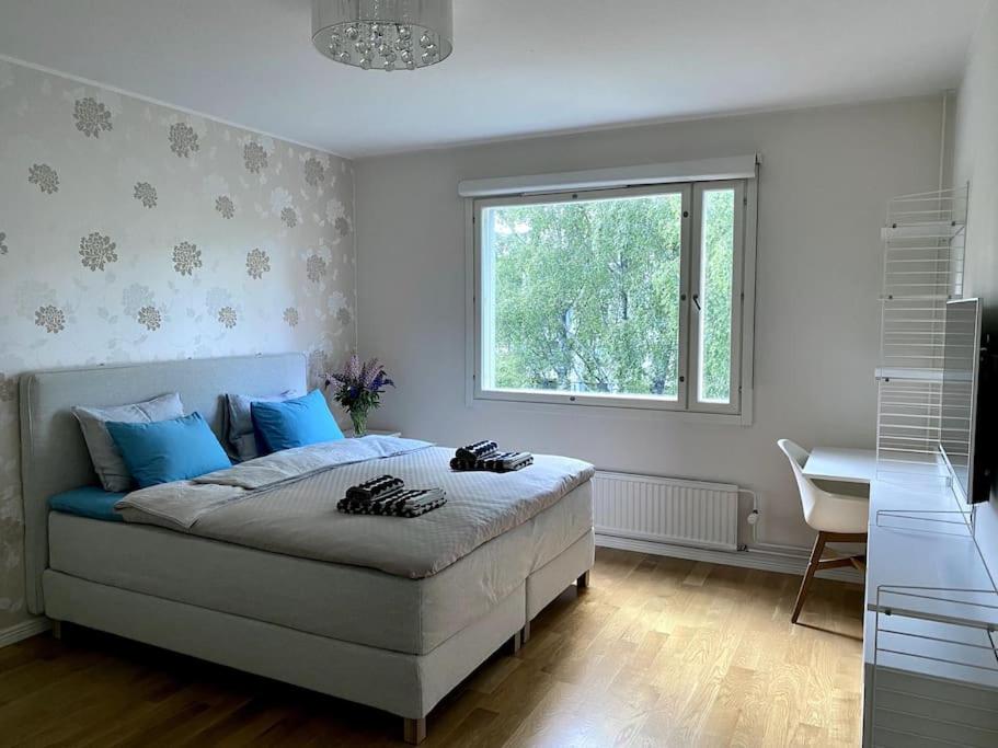 Un dormitorio con una cama con almohadas azules y una ventana en 2 br apartment w/ balcony, wifi, parking en Espoo