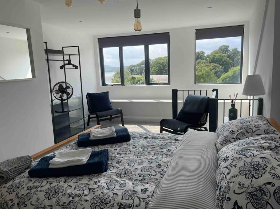 a bedroom with a bed with two chairs and windows at ROOMZ TOWNHOUSE NO 20 in Portaferry