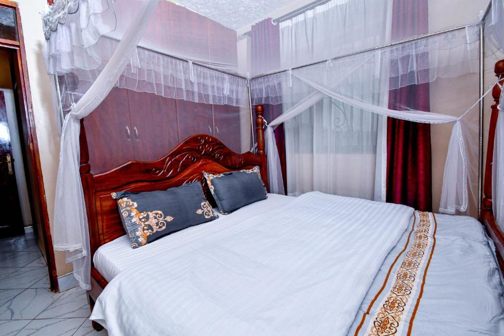 Peace of Mind Suites في عنتيبي: غرفة نوم مع سرير أبيض مع لوحة على الرأس الأحمر